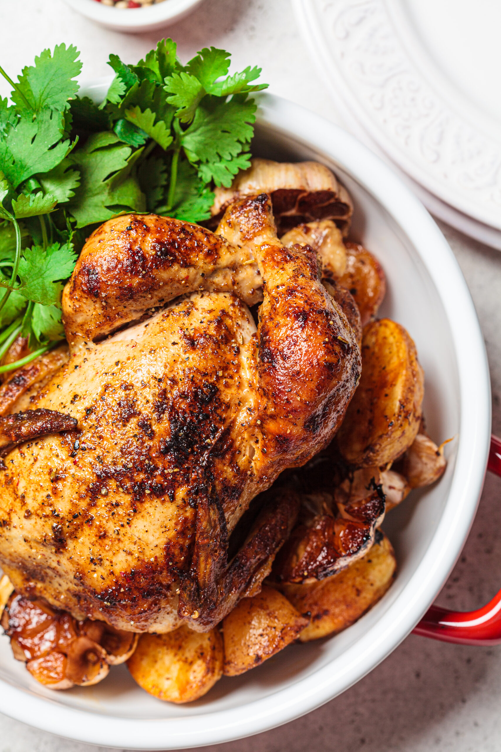 Christmas cooked chicken with potatoes in a red pot, top view. Festive homemade food concept.