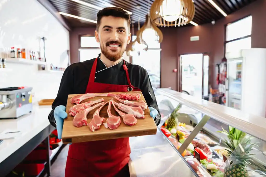 young butcher holding raw lamb ribs in a butcher s 2023 11 27 05 24 31 utc 1
